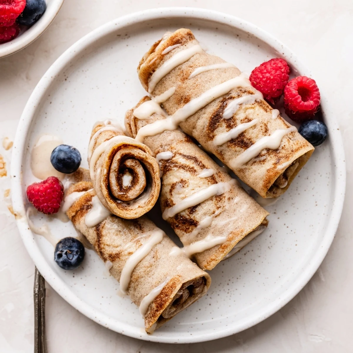 Warm Cinnamon Roll Protein Crepes rolled with creamy cinnamon filling and glaze