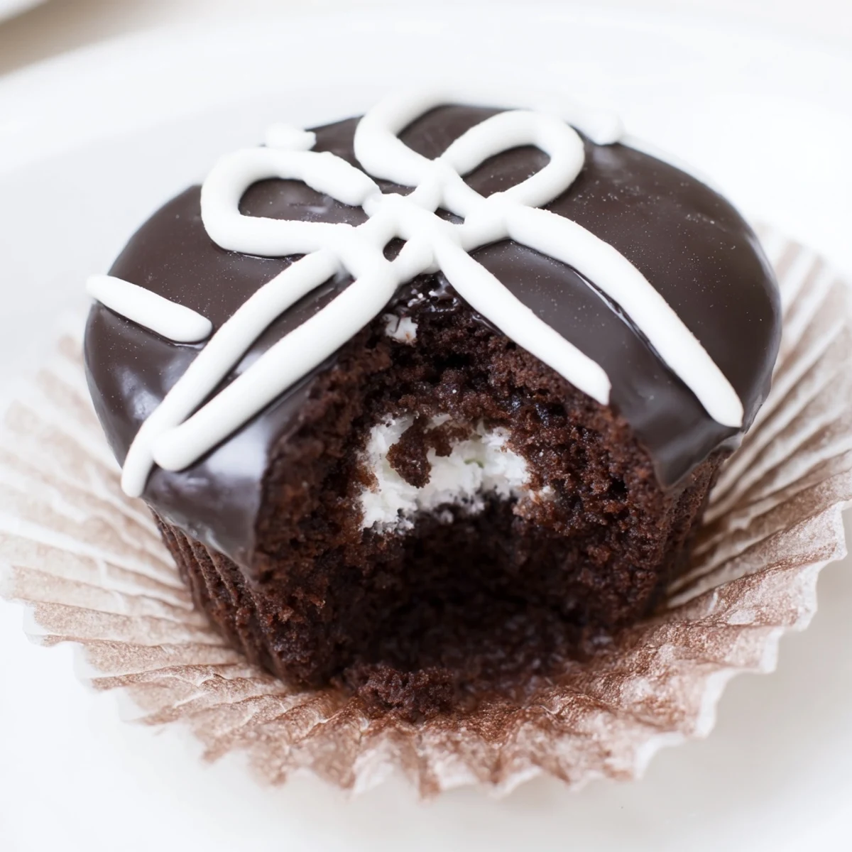 Classic Homemade Hostess Cupcakes drizzled in rich chocolate glaze on a rustic plate