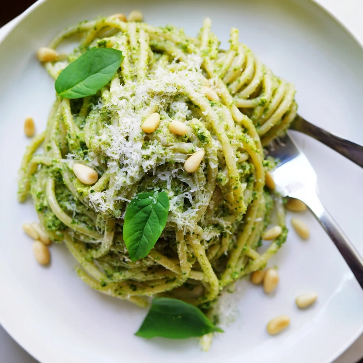 Creamy wild garlic pesto pasta twirled on a fork with fresh Parmesan shavings
