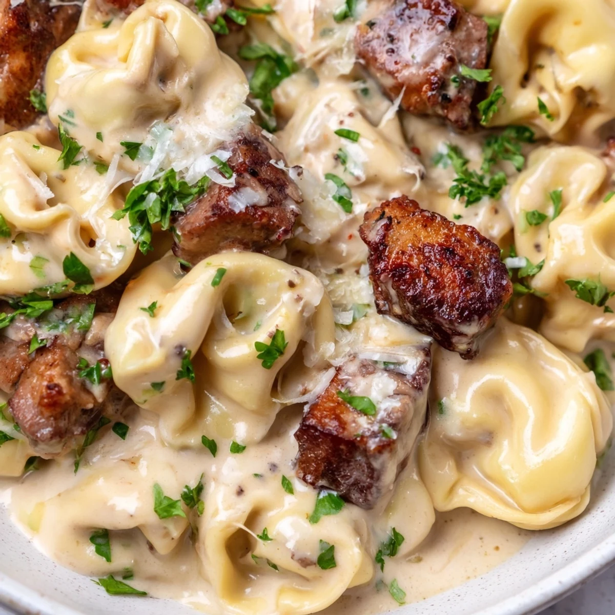 Garlic steak tortellini plated with creamy garlic sauce and fresh parsley garnish