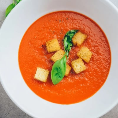 A steaming bowl of Creamy Tomato and Basil Soup with Croutons, perfect for a cozy vegetarian dinner paired with crusty bread.  